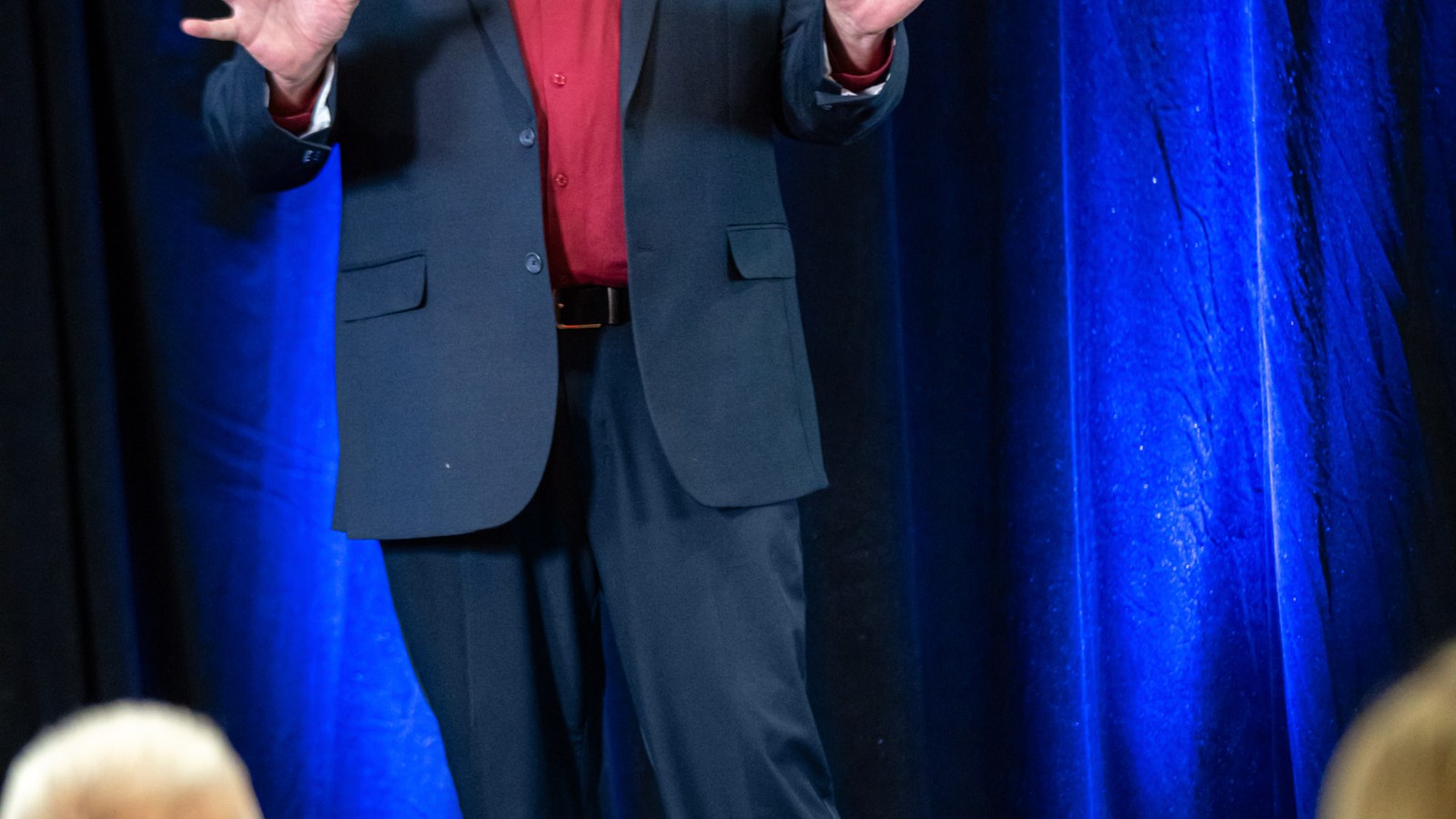 Ted Simmons speaking on stage with blue lights, hands raised